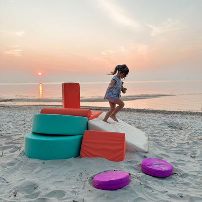 Girl running down a play couch build with adventurer covers on at the beach 