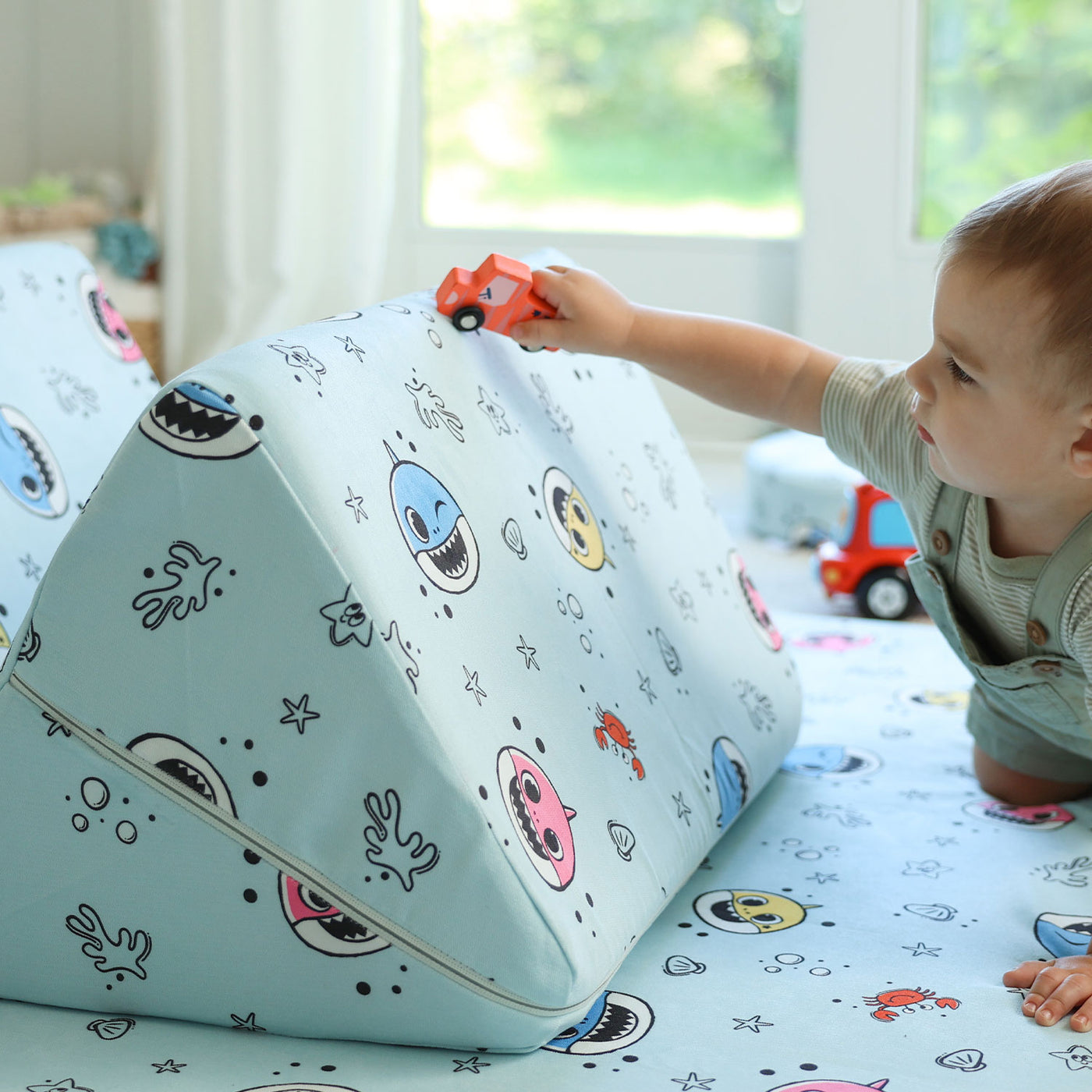 Toddler driving a toy car on the Baby Shark™ x Roo & You™ Joey Play Couch.